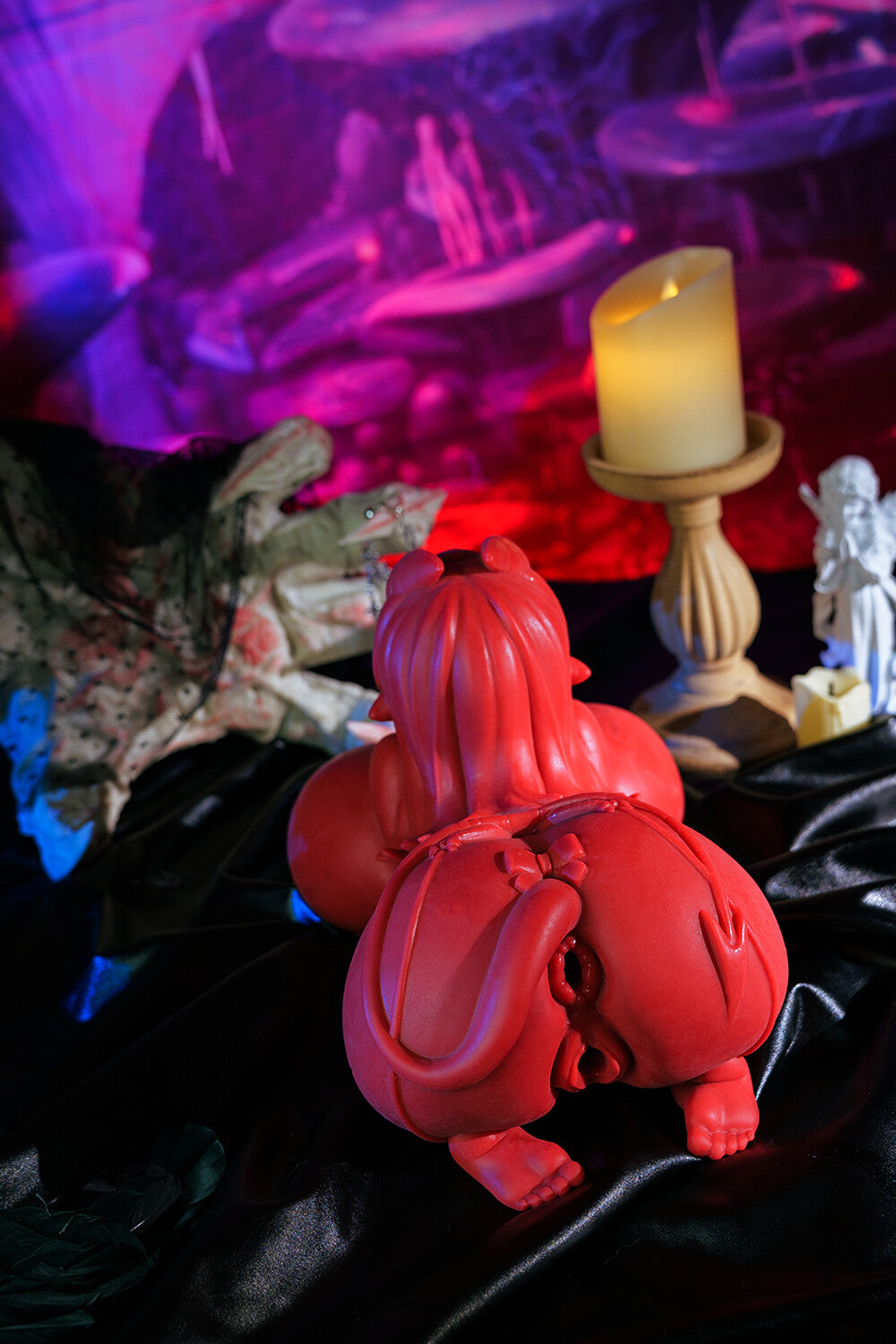 Image of The red Meru anal sex toy set in a dark, gothic scene with candlelight and statues.