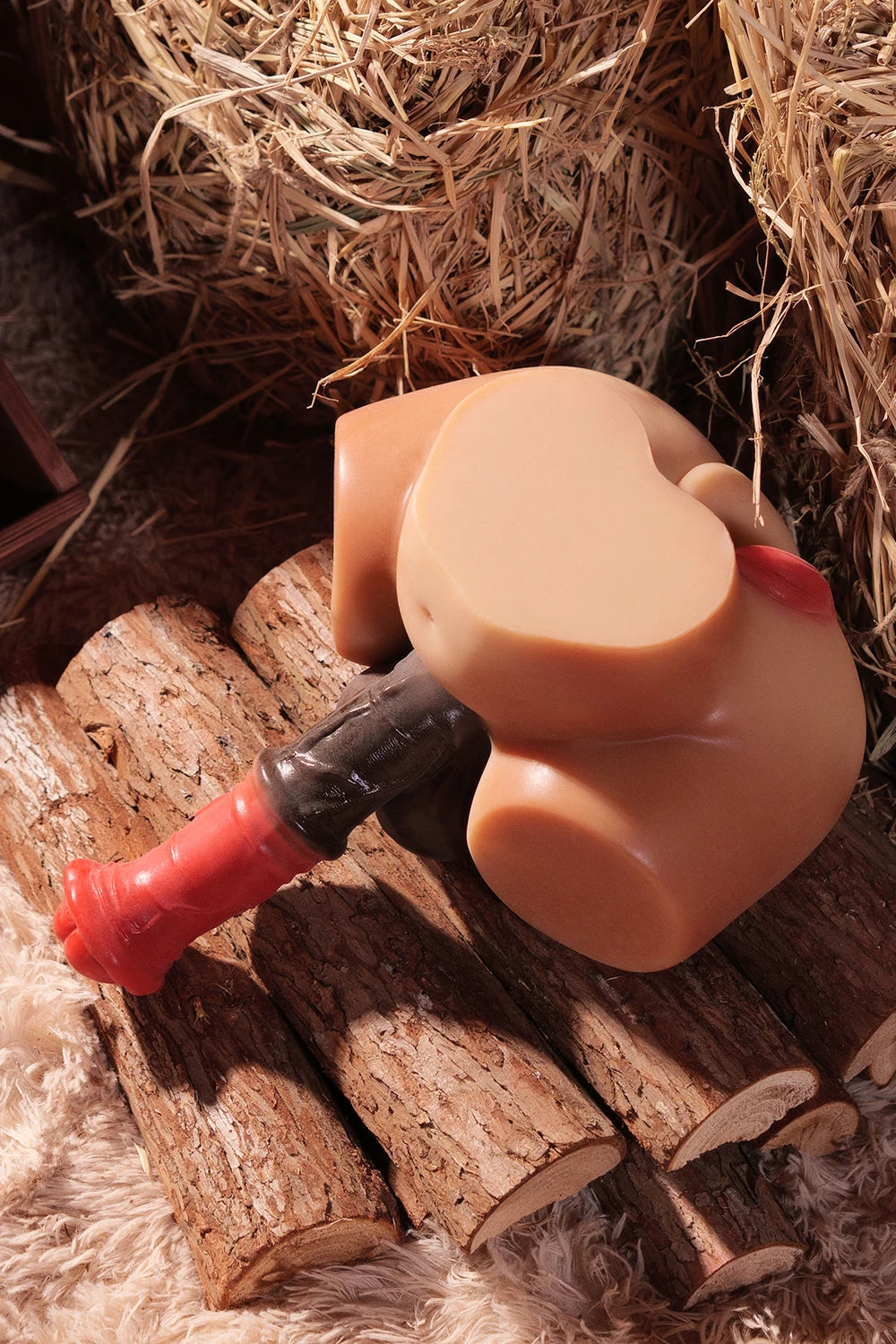 Image of The Bonnie futa sex doll torso with huge dick lying on its side on logs and hay.